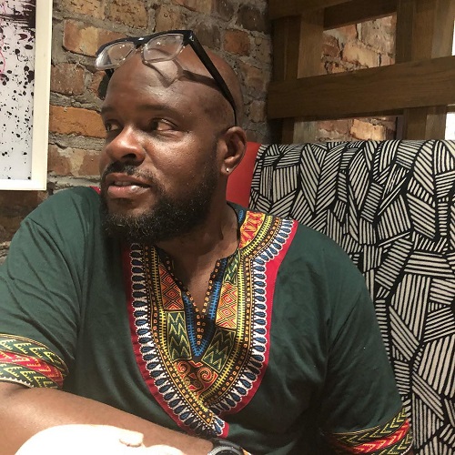 Image of Black man with glasses and dark green shirt.