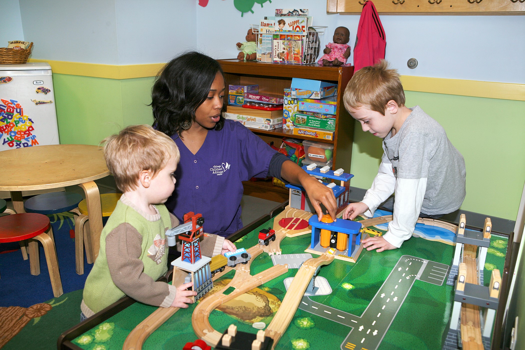 Woman in classroom playing with two children