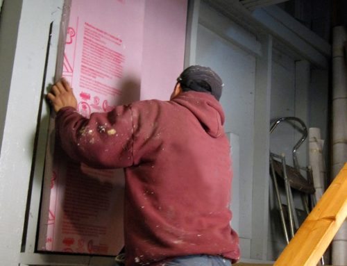 Person installing wall insulation at a home.