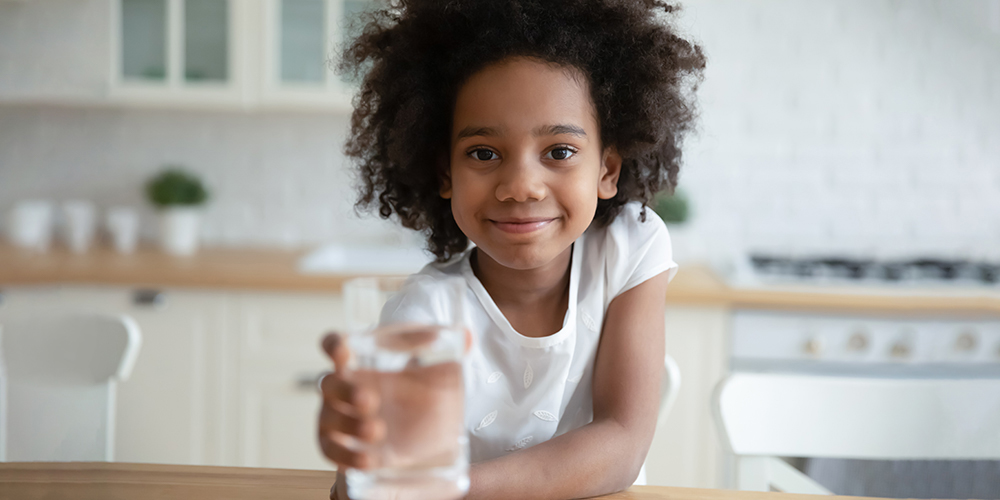 child holding a glass of drinking water 