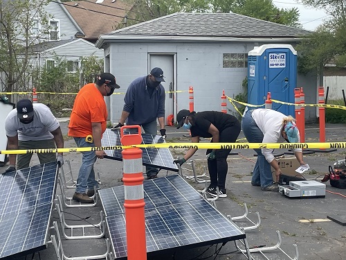 Group of students working on a large solar panel at a construction site