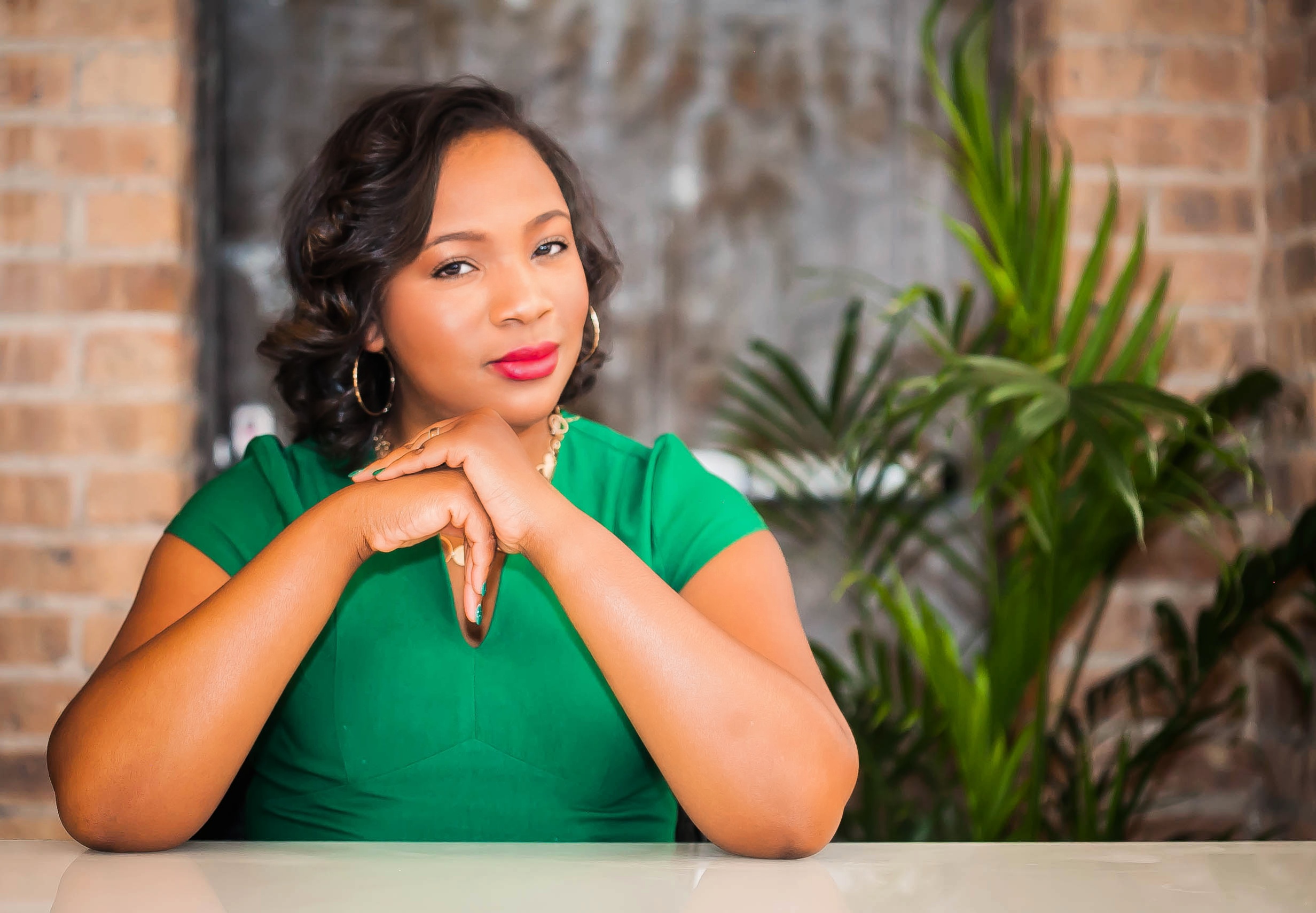 Black woman sitting and resting her head on her hands, looking at the camera