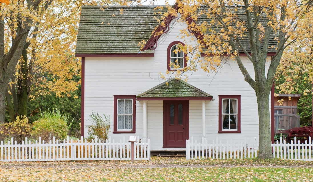 White and red wooden house with fall trees - Spanish
