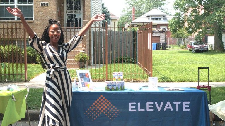 Vetia Hill at a table with a tablecloth that says "Elevate"