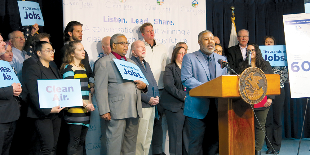 Delmar Gillus at a podium surrounded by peers 