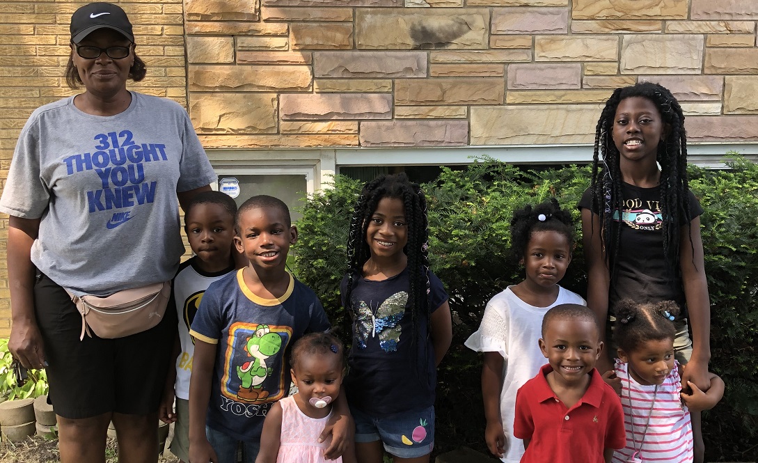 Photo of child care provider with a group of children in the front yard of a home.