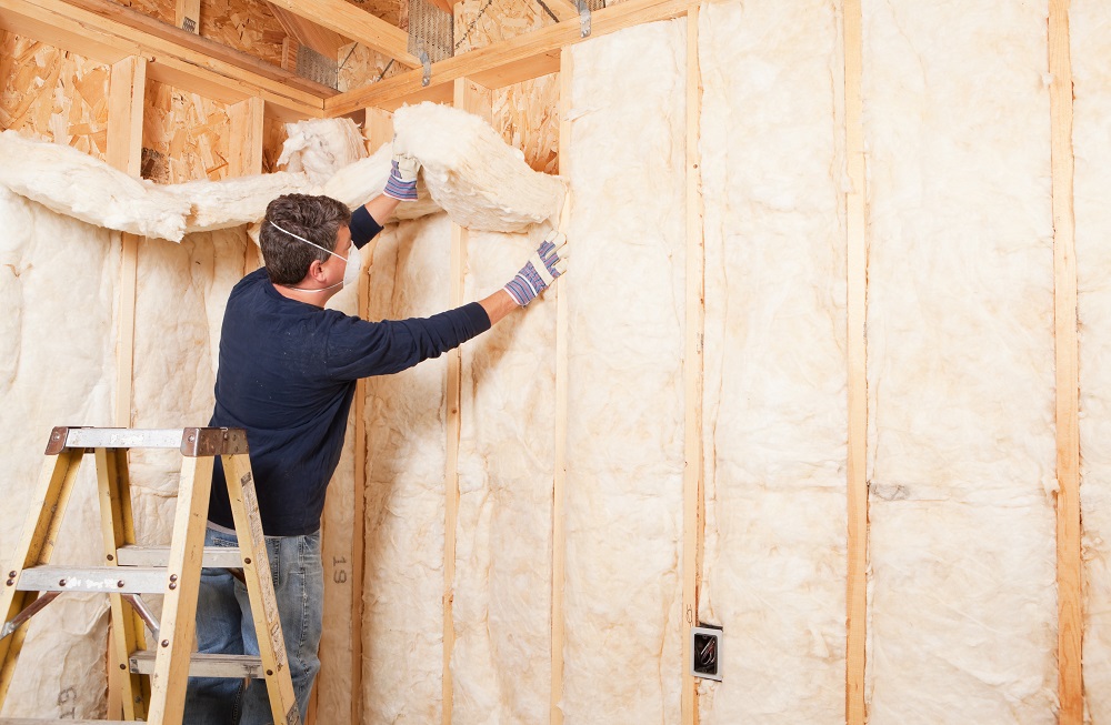 Construction Worker Insulating Wall with Fiberglass Batt 