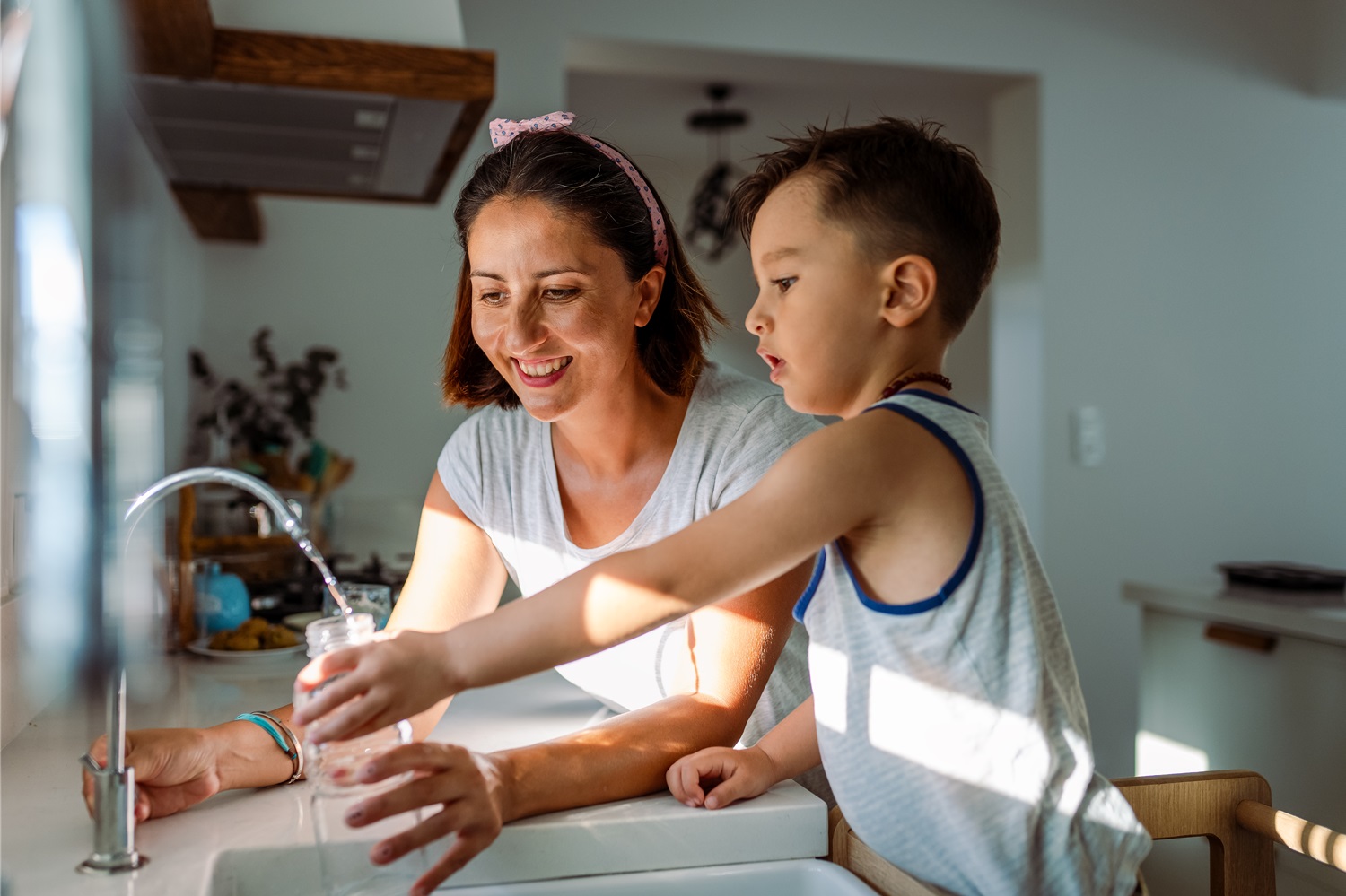 Mother and her toddler filling a glass with filtered water right from the tap