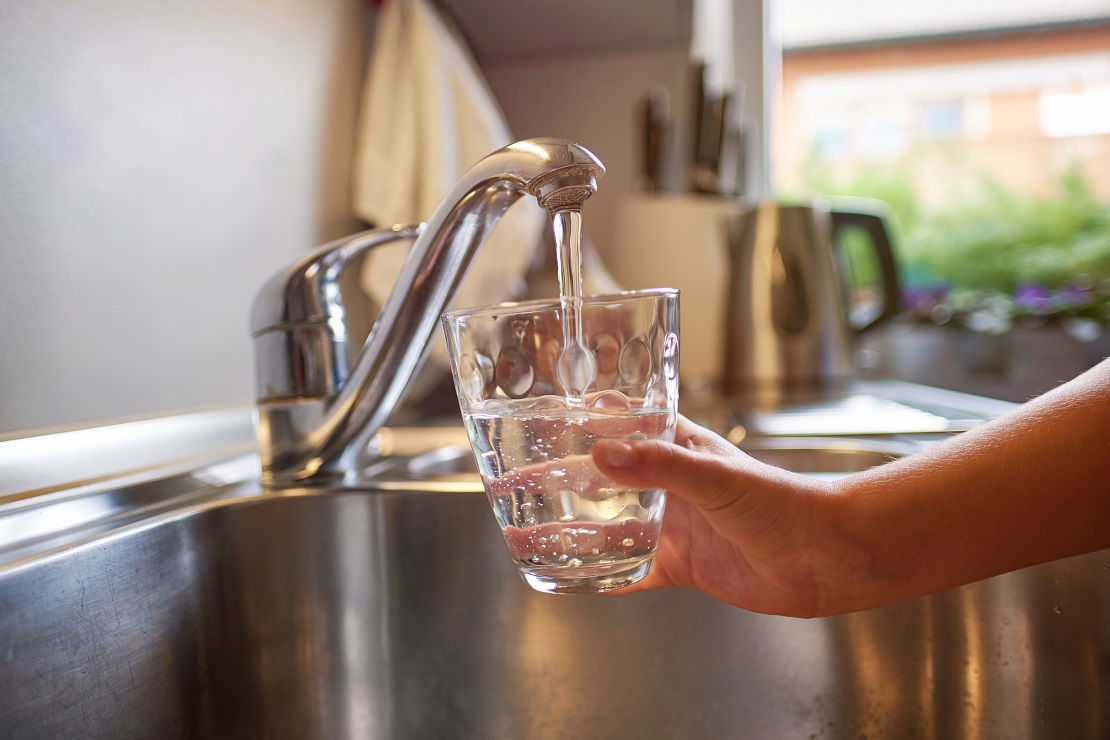 Close up of children hands, pouring glass of fresh water from tap in kitchen