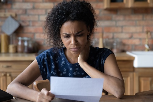 Close up unhappy African American young woman reading letter, document, frustrated businesswoman or student received bad news, unexpected debt or job dismissal notification, financial problem
