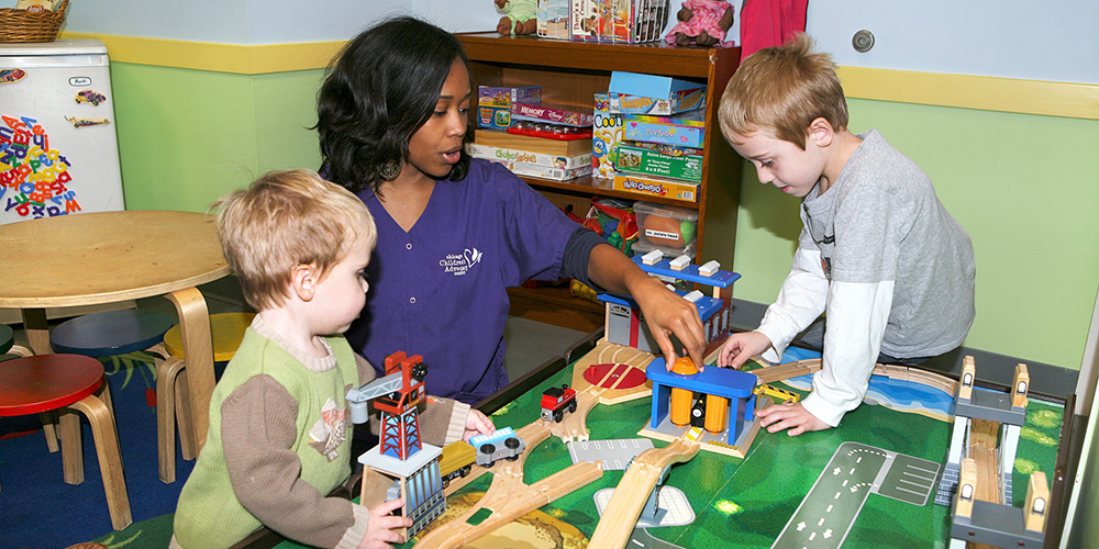 woman working with children at a play table 